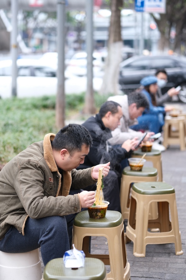 12月2日，南岸區(qū)銅元局長江村，街頭一小面館，市民在路旁吃面。郭旭攝