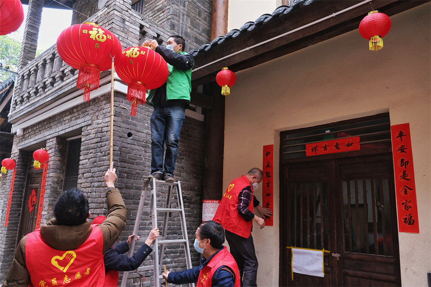 志愿者們正在為黃葛古道敦厚坡段的傳統(tǒng)民居懸掛燈籠。郭旭攝