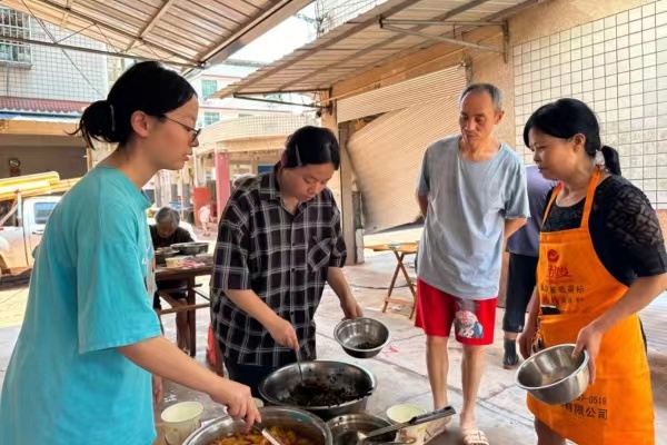 趙英潔（左二）、趙彬潔（左一）姐妹正在忙著分裝熱菜。潼南區(qū)委宣傳部供圖