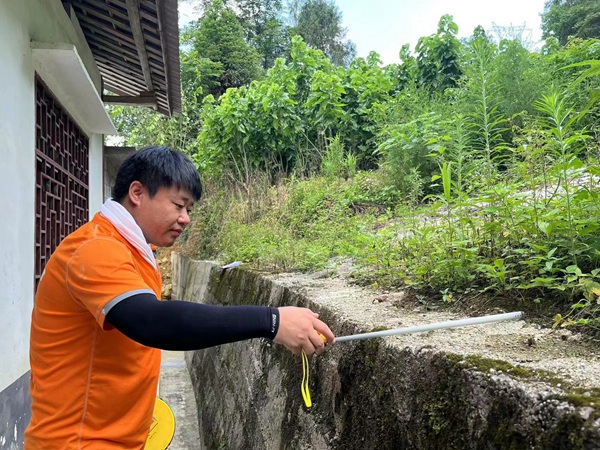 《實測實量》。7月29日，川東南勘察公司駐守地質(zhì)工程師曹志遠在黔江區(qū)阿蓬江鎮(zhèn)分水村，對陸家河滑坡范圍內(nèi)的居民房屋后邊坡已建擋墻的寬度進行實測。王龍貴攝