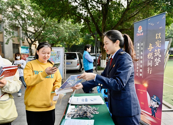 11月29日，在重慶工商大學(xué)（江北校區(qū)），江北區(qū)稅務(wù)人員引導(dǎo)學(xué)生掃碼了解憲法知識(shí)。曾鈺翀攝