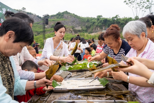 游人和村民在包粽子迎端午。秦廷富 攝