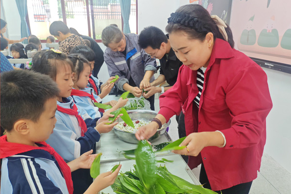 學生同家長、老師一起參加端午節(jié)包粽子傳統(tǒng)文化活動。雙福六小供圖