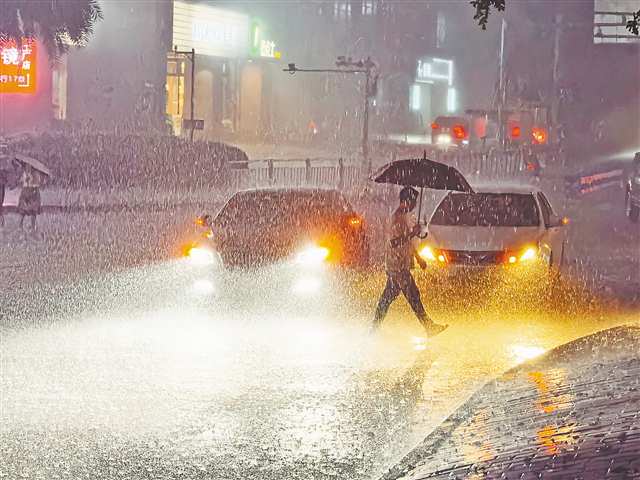 7月13日晚，渝北區(qū)獅子坪輕軌站，市民撐傘在暴雨中走過。當(dāng)晚，主城區(qū)出現(xiàn)雷電暴雨天氣。記者 劉力 攝/視覺重慶